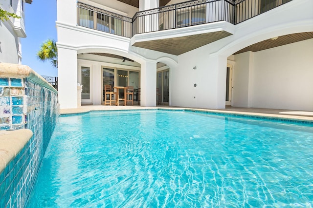 outdoor pool with outdoor dry bar, a patio area, and a ceiling fan