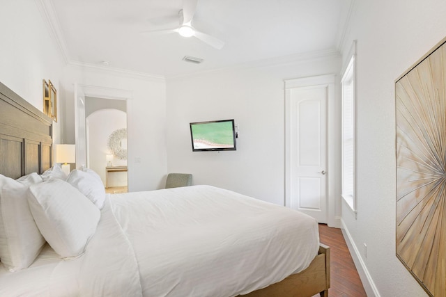 bedroom with arched walkways, visible vents, ornamental molding, wood finished floors, and baseboards