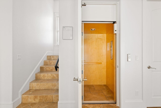 stairway featuring baseboards and elevator