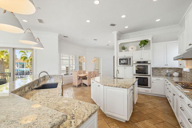 kitchen featuring a kitchen island with sink, stone tile floors, a sink, appliances with stainless steel finishes, and open shelves