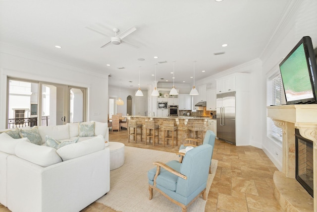 living room with arched walkways, crown molding, stone tile floors, and a premium fireplace