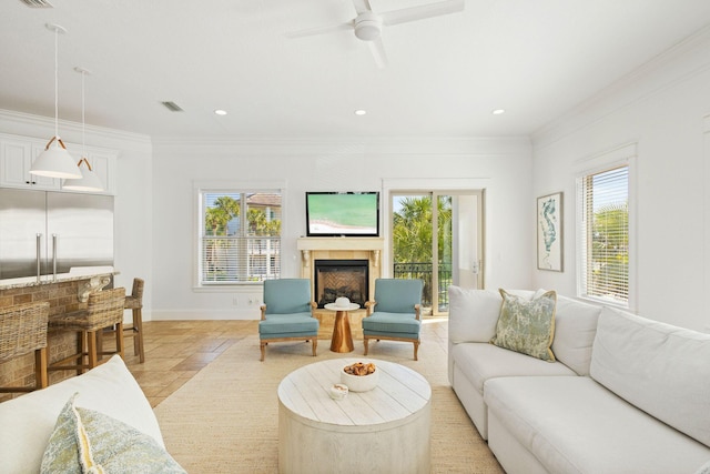 living area with stone tile floors, a fireplace, visible vents, baseboards, and ornamental molding