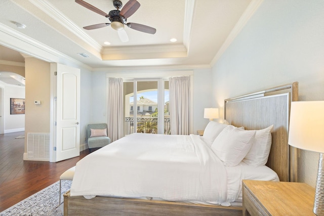 bedroom with visible vents, arched walkways, hardwood / wood-style floors, access to outside, and a tray ceiling