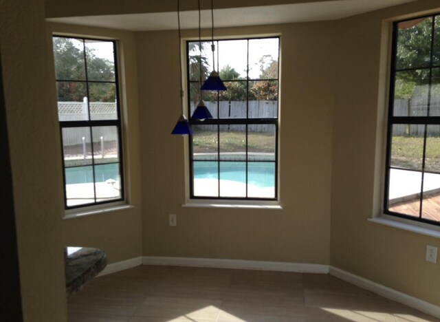 unfurnished dining area featuring baseboards, plenty of natural light, and tile patterned flooring