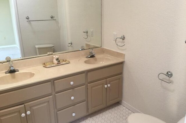 bathroom with double vanity, toilet, and a sink