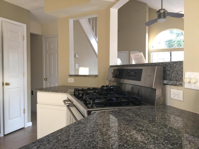 kitchen featuring white cabinetry, dark stone counters, and stainless steel gas range