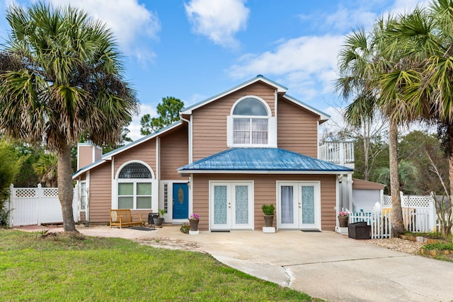 view of front of home with a front lawn, french doors, fence, and metal roof