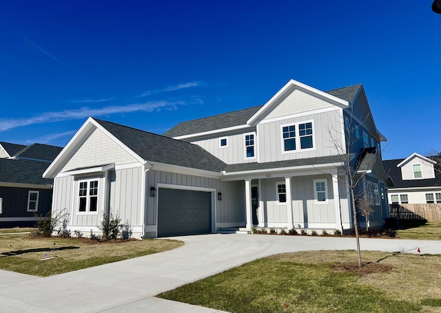 modern farmhouse style home featuring a garage, concrete driveway, covered porch, board and batten siding, and a front yard