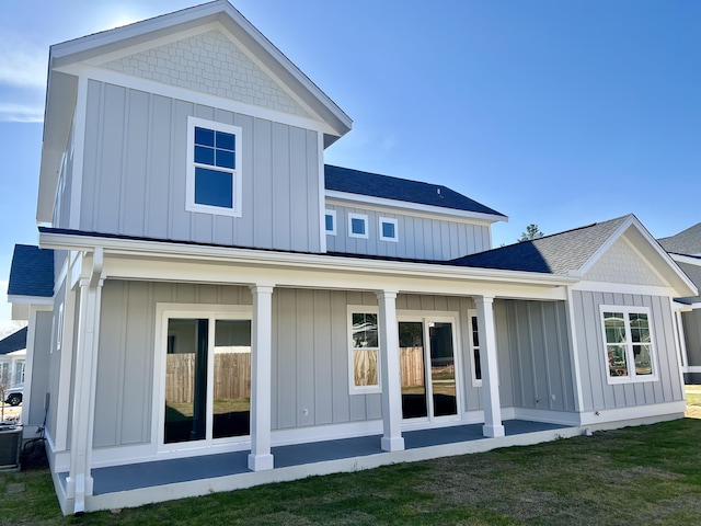 rear view of house featuring a shingled roof, board and batten siding, and a yard