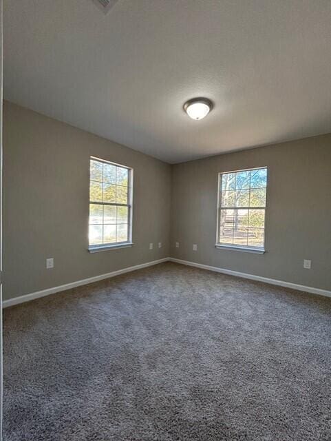 carpeted spare room featuring plenty of natural light and baseboards