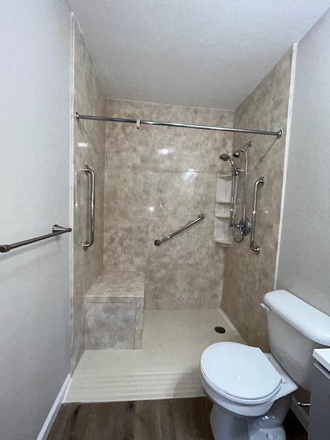 bathroom featuring a stall shower, wood finished floors, and toilet