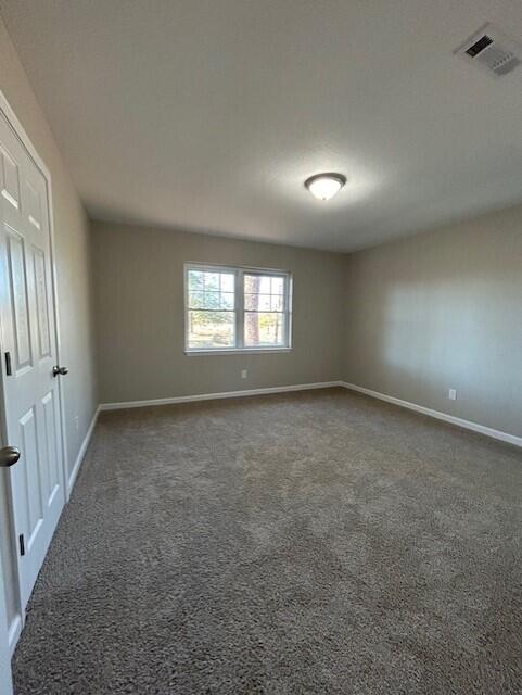 carpeted empty room with baseboards and visible vents