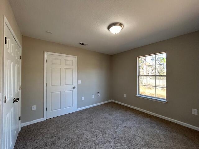 unfurnished bedroom with carpet, visible vents, and baseboards