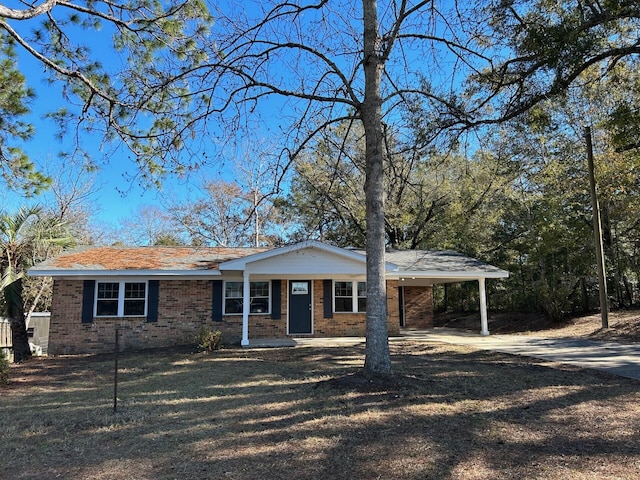 view of front of property featuring driveway, a front lawn, an attached carport, and brick siding