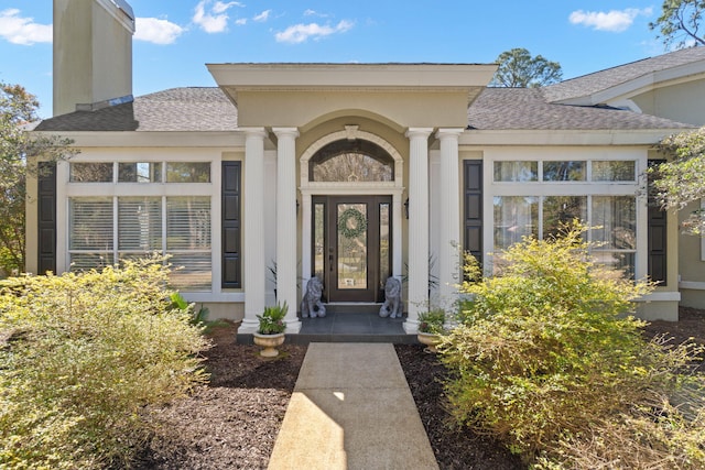 property entrance with a chimney and a shingled roof