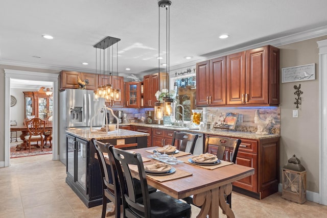 kitchen with light stone counters, an island with sink, a sink, stainless steel appliances, and crown molding