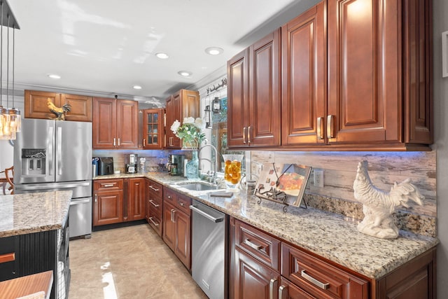 kitchen featuring tasteful backsplash, glass insert cabinets, light stone countertops, stainless steel appliances, and a sink