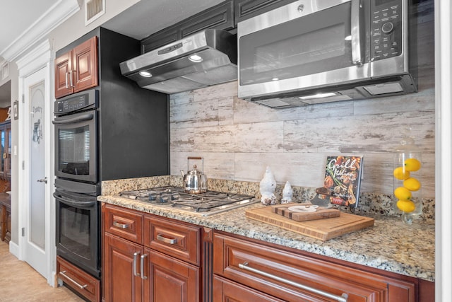 kitchen featuring under cabinet range hood, light stone counters, tasteful backsplash, and appliances with stainless steel finishes