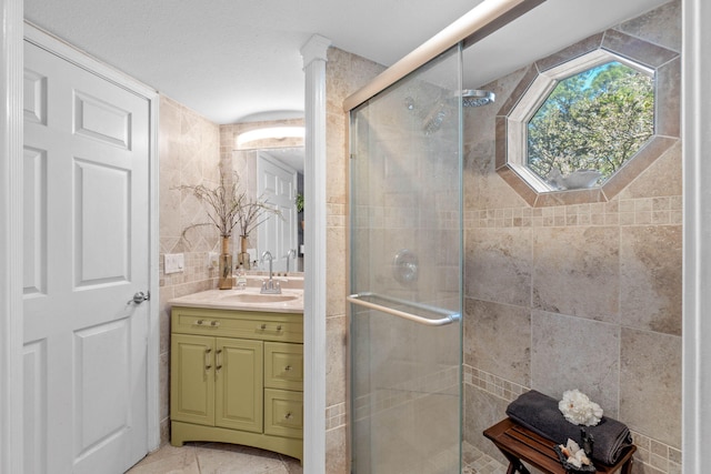 full bath featuring vanity, tile walls, and a shower stall