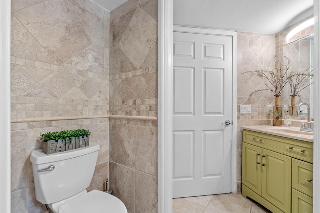 bathroom featuring vanity, tile walls, toilet, and tile patterned flooring