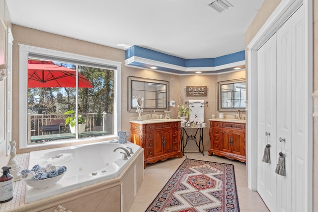 bathroom featuring tile patterned flooring, visible vents, a jetted tub, and a sink