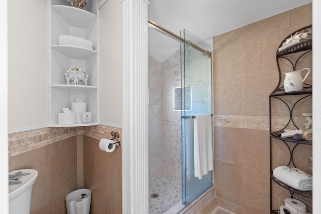 full bath featuring toilet, a stall shower, and tile walls