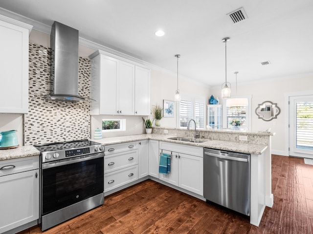 kitchen with visible vents, a sink, ornamental molding, stainless steel appliances, and wall chimney exhaust hood