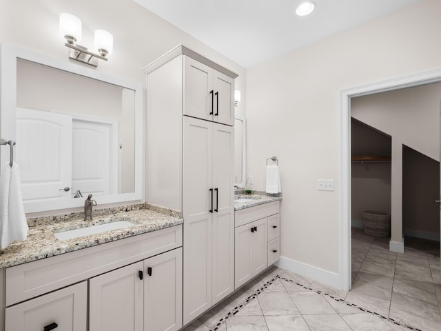 full bathroom with marble finish floor, two vanities, baseboards, and a sink