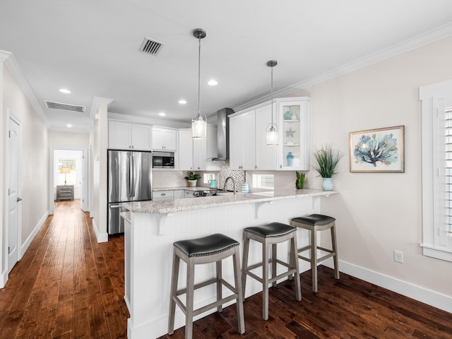 kitchen with visible vents, wall chimney range hood, a peninsula, stainless steel appliances, and dark wood-style flooring