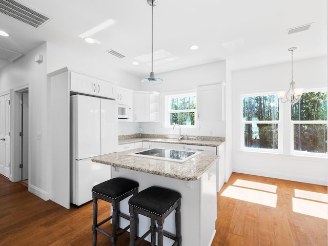 kitchen with white appliances, white cabinets, and visible vents