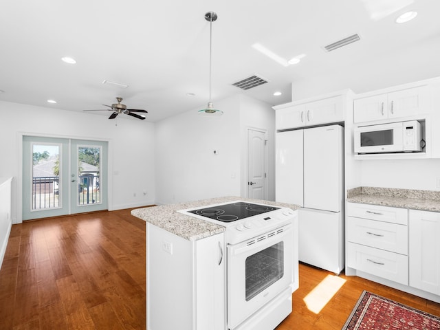 kitchen featuring visible vents, white appliances, light wood-style flooring, and a center island