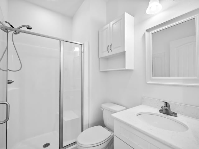 full bathroom with vanity, a shower stall, and toilet