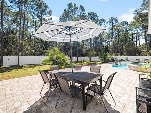 view of patio / terrace with a fenced backyard, outdoor dining space, and a pool with connected hot tub