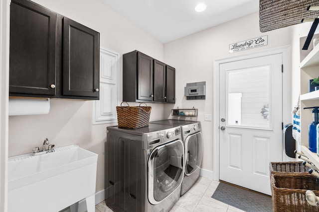 clothes washing area featuring a sink, cabinet space, baseboards, and washer and clothes dryer