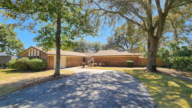 view of front of house with a garage, driveway, brick siding, and fence