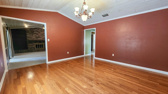 spare room with visible vents, lofted ceiling, ornamental molding, light wood-type flooring, and a fireplace