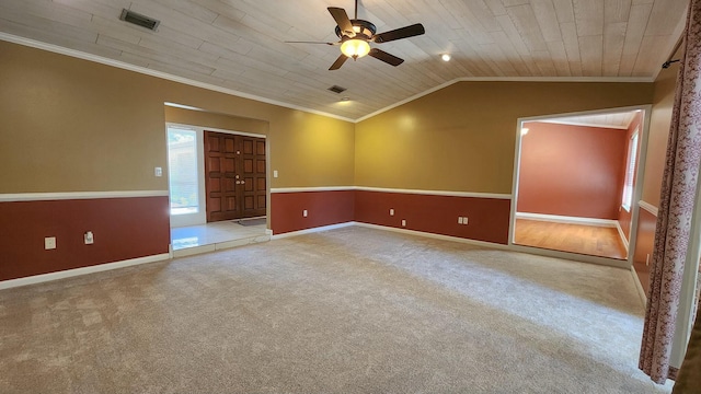 carpeted spare room featuring lofted ceiling, visible vents, and crown molding