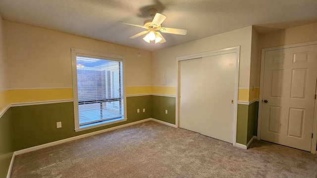 unfurnished bedroom featuring ceiling fan, a textured ceiling, carpet floors, baseboards, and a closet