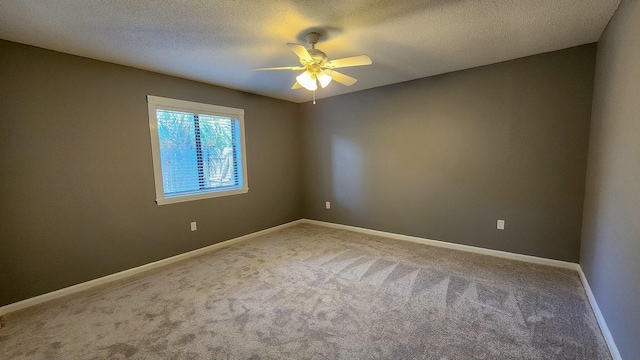 carpeted empty room with a ceiling fan, baseboards, and a textured ceiling