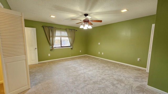 spare room with a ceiling fan, carpet flooring, a textured ceiling, and baseboards