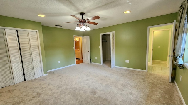 unfurnished bedroom featuring a closet, light carpet, visible vents, and a textured ceiling