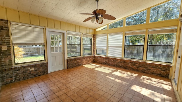 unfurnished sunroom with a ceiling fan and vaulted ceiling