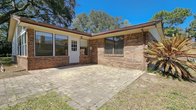 back of property featuring brick siding and a patio area