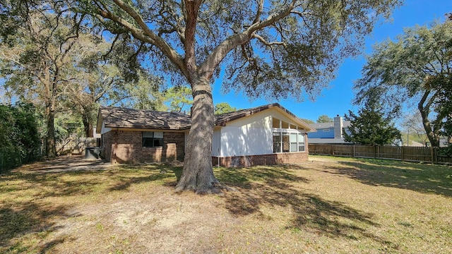 exterior space featuring brick siding, a lawn, and a fenced backyard