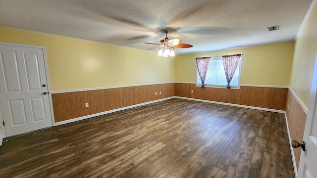 empty room featuring a wainscoted wall, a textured ceiling, wood finished floors, and wood walls