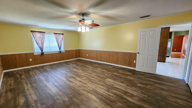 empty room with a wainscoted wall, visible vents, and a textured ceiling