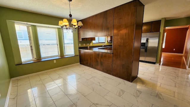 kitchen with marble finish floor, stainless steel refrigerator with ice dispenser, dark countertops, hanging light fixtures, and a chandelier