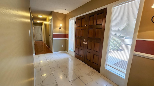 foyer entrance with marble finish floor and baseboards