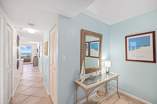 hall with light tile patterned flooring and baseboards