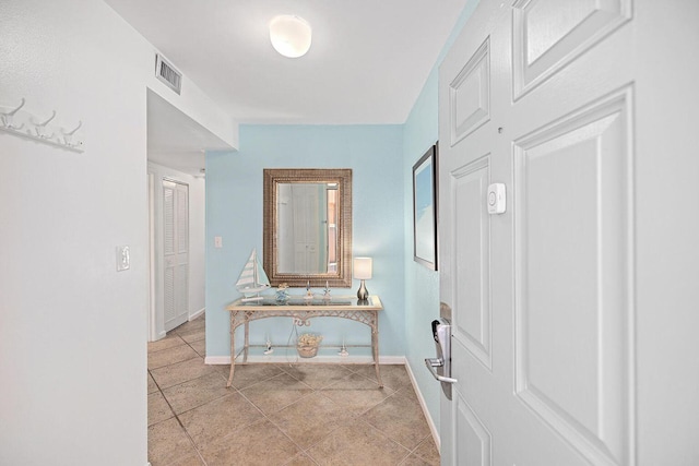 hallway featuring light tile patterned flooring, visible vents, and baseboards